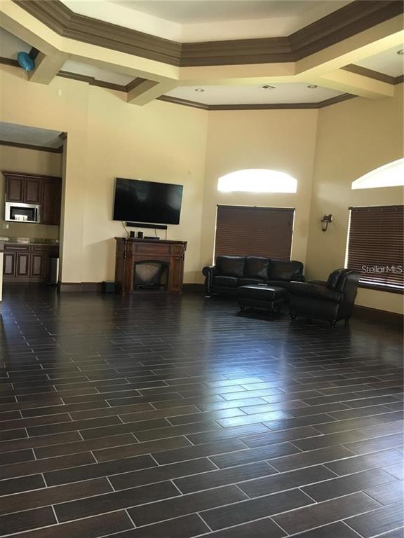 A spacious living room features dark wood-look tile flooring, a fireplace, and a tray ceiling — 14049 FAIRWAY ISLAND DRIVE UNIT 127, ORLANDO, FL