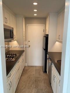 A narrow galley kitchen features white cabinets, dark countertops, a gas cooktop, and stainless appliances — 700 Biltmore Way # 219, Coral Gables FL 33134, CORAL GABLES, FL