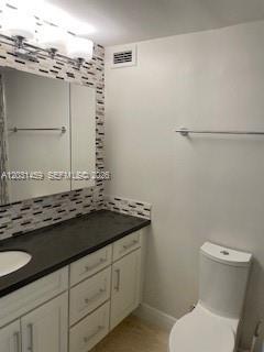 A bathroom features a white vanity with a dark countertop, a mirror, and a toilet — 700 Biltmore Way # 219, Coral Gables FL 33134, CORAL GABLES, FL