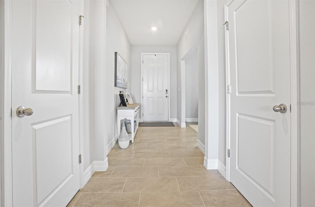 A bright hallway features light tile flooring, white doors, and a small console table — 17925 FATTORIA TERRACE, LAKEWOOD RANCH, FL