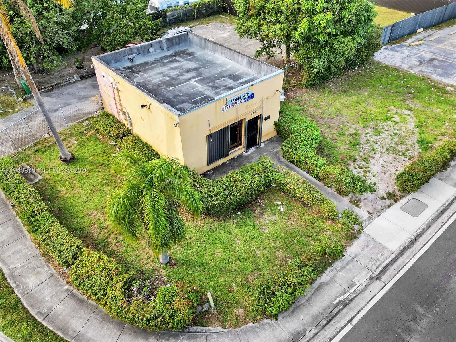An aerial view of a small, yellow, flat-roofed commercial building surrounded by landscaping and grass — 9200 NW 22nd Ave, Miami FL 33147, MIAMI, FL