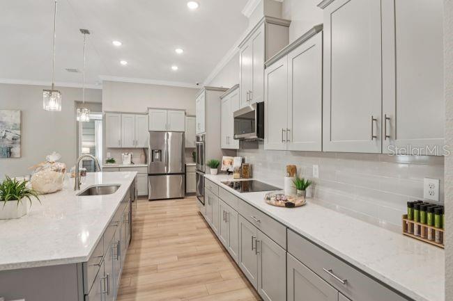 A modern kitchen features light gray cabinets, white quartz countertops, and stainless steel appliances — 17041 ROYAL PALMS DRIVE, GROVELAND, FL