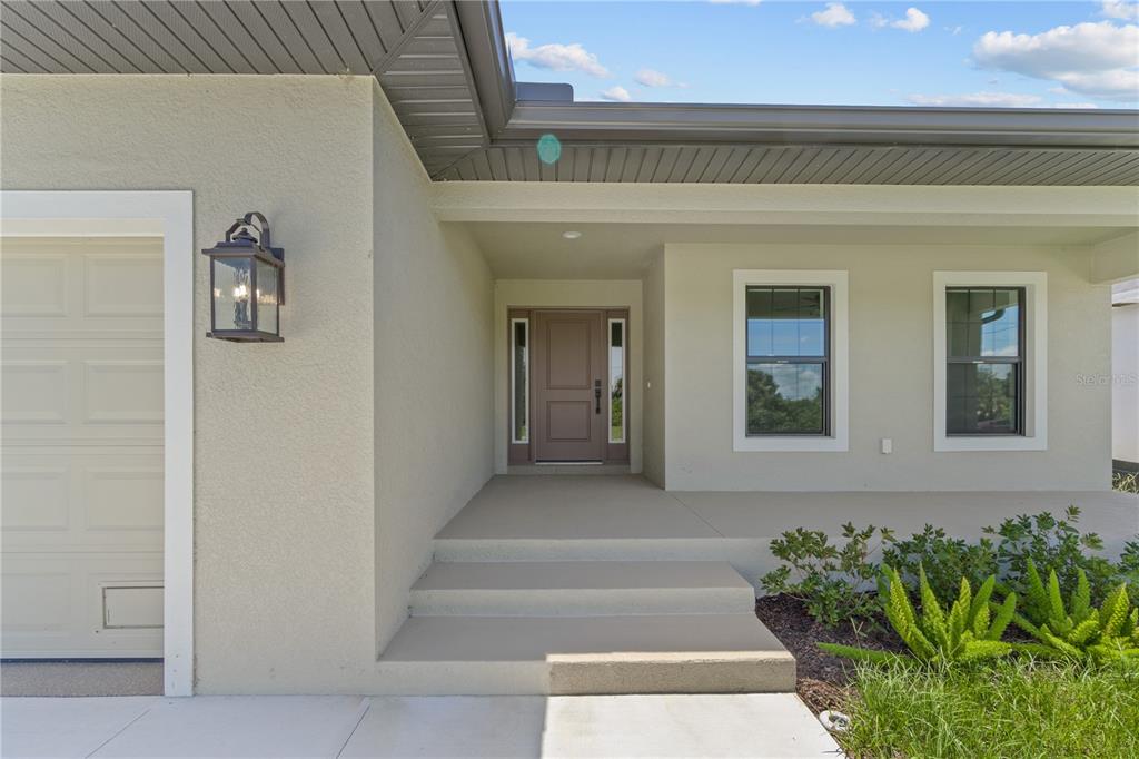 The exterior of a house features a tan front door, two steps, and a porch — 196 ARCH DRIVE, ROTONDA WEST, FL