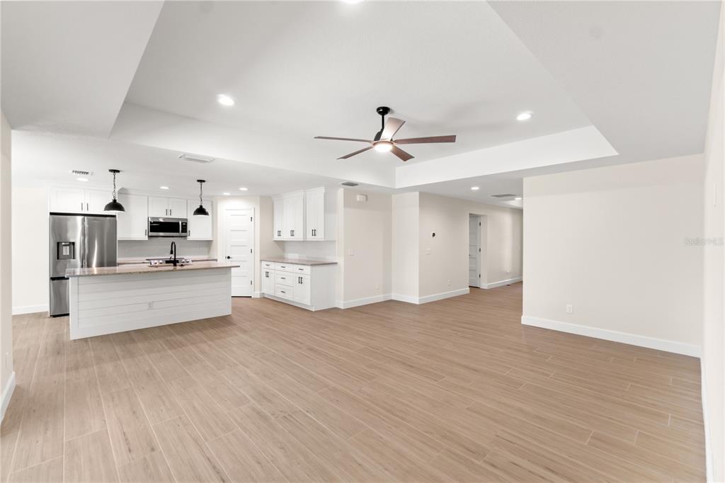 An open-concept kitchen and living area features white cabinetry, a kitchen island, and wood-look flooring — 196 ARCH DRIVE, ROTONDA WEST, FL