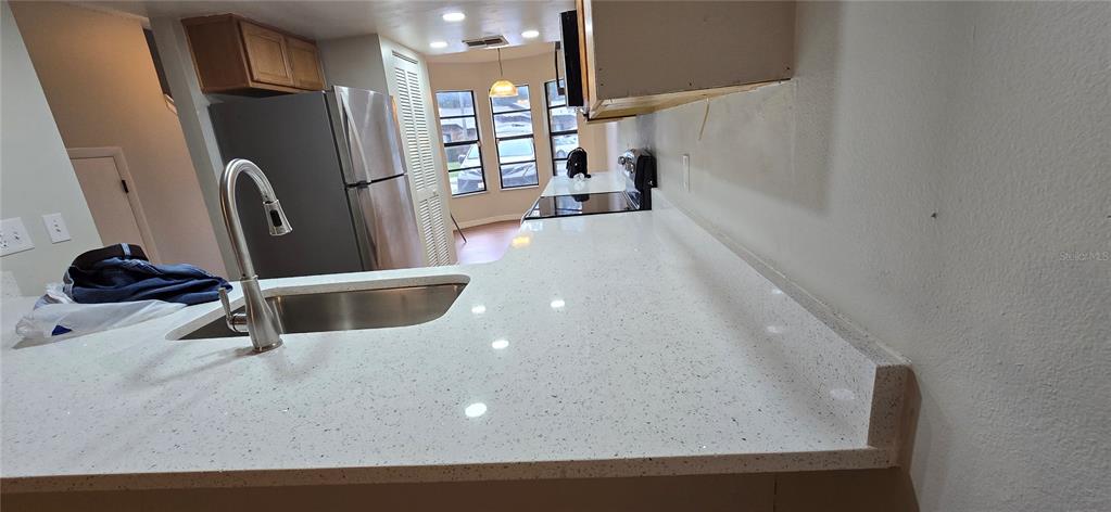A kitchen features white quartz countertops, a stainless steel sink, and a stainless steel refrigerator — 1834 FOXHALL CIRCLE, KISSIMMEE, FL