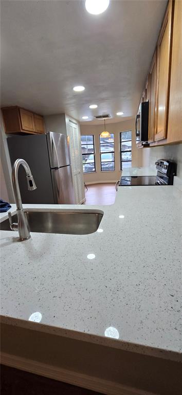 A kitchen features white speckled countertops, a stainless steel sink, and light wood cabinetry — 1834 FOXHALL CIRCLE, KISSIMMEE, FL