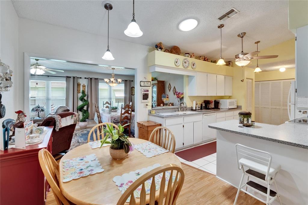 A kitchen with white cabinets and a dining area featuring a round wooden table — 3154 PRAIRIE DUNES CIRCLE W, LAKELAND, FL