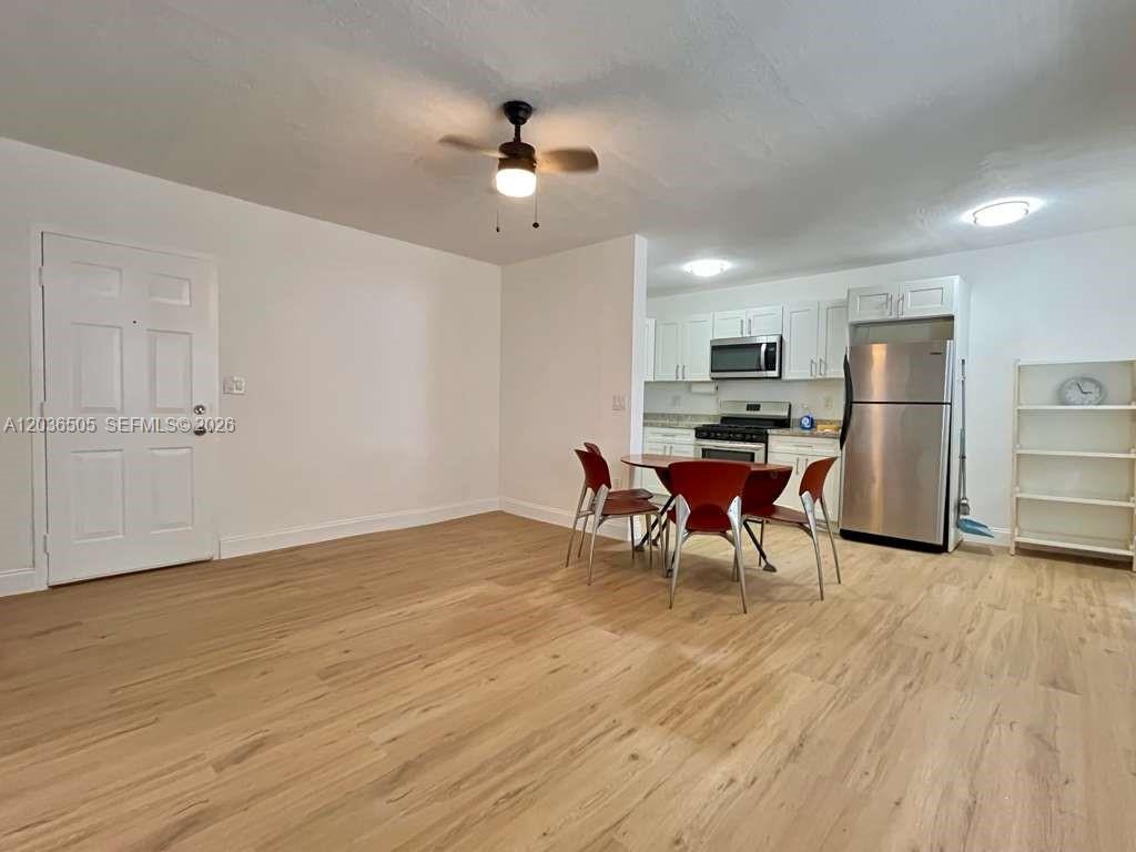 A dining area with wood-look flooring, a ceiling fan, and an adjacent open kitchen — 7928 Harding Ave # 3, Miami Beach FL 33141, MIAMI BEACH, FL