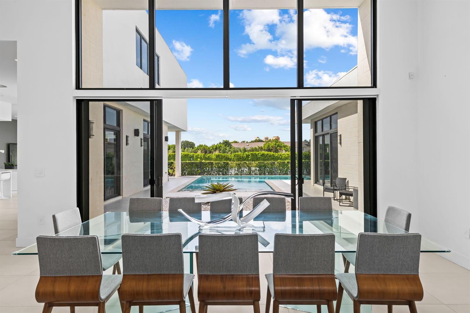 A dining room with a glass table and chairs overlooks a patio and swimming pool — 16768 Natures Way, Weston FL 33326, WESTON, FL
