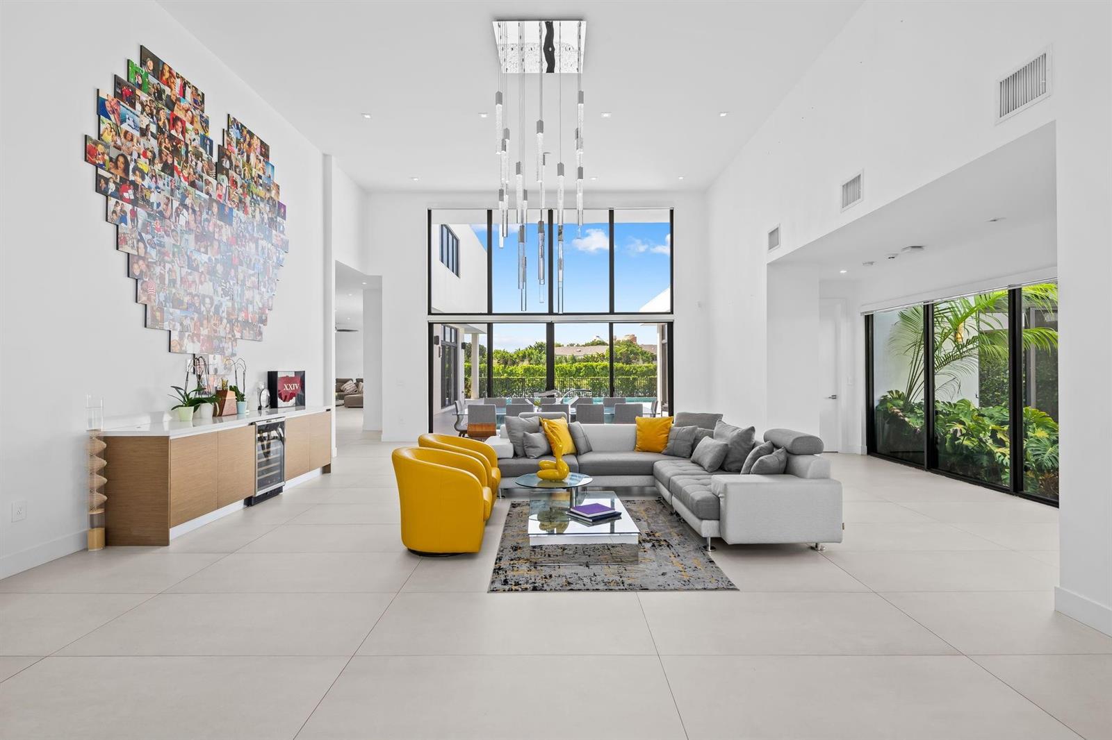 A spacious, modern living room features white walls, tile floors, yellow chairs, and a photo collage — 16768 Natures Way, Weston FL 33326, WESTON, FL