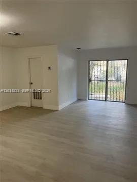 An interior view of a room with light-colored flooring, a white door, and sliding glass doors — 20922 NW 39th Ave, Miami Gardens FL 33055, MIAMI GARDENS, FL