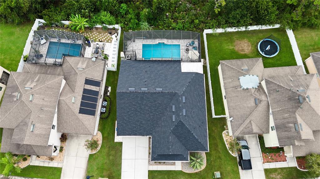 An aerial view shows three suburban houses with swimming pools and fenced backyards — 2651 MARSHFIELD PRESERVE WAY, KISSIMMEE, FL