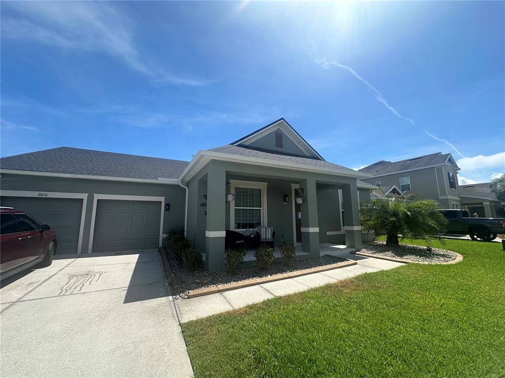 A single-story house with a green exterior, two-car garage, and a covered front porch — 2651 MARSHFIELD PRESERVE WAY, KISSIMMEE, FL