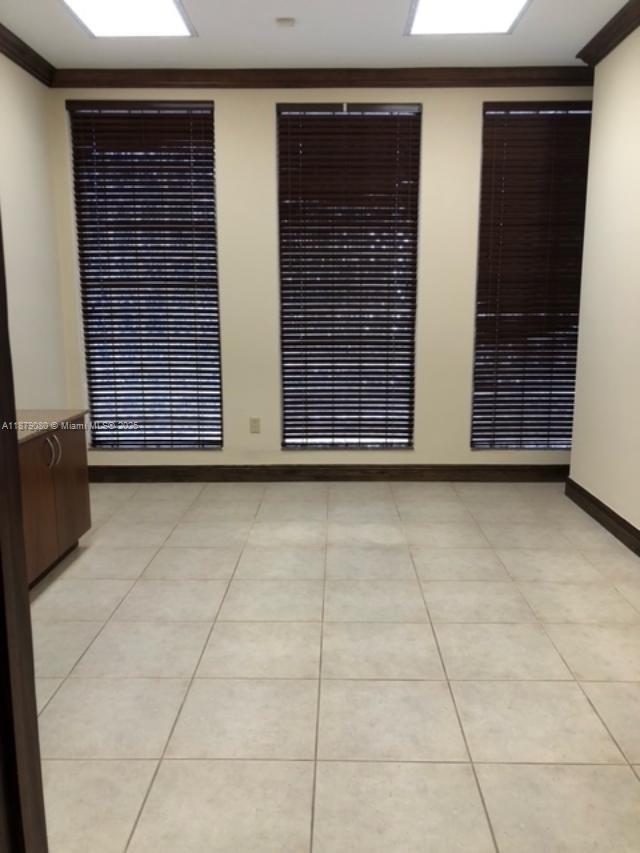An office room features light tile flooring, three windows with dark blinds, and crown molding — 35 Almeria Ave, Coral Gables FL 33134, CORAL GABLES, FL