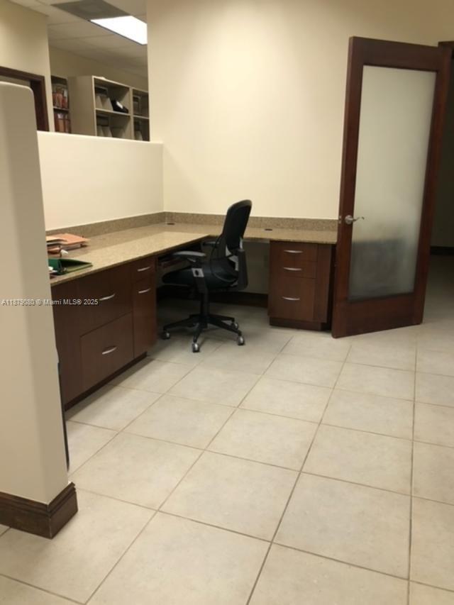 An office space features an L-shaped desk with dark wood cabinetry and a rolling chair — 35 Almeria Ave, Coral Gables FL 33134, CORAL GABLES, FL