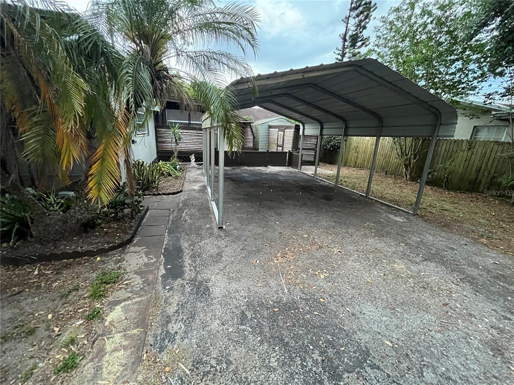 A metal carport stands over a paved driveway next to a house and palm tree — 5325 LIME AVENUE, SEFFNER, FL