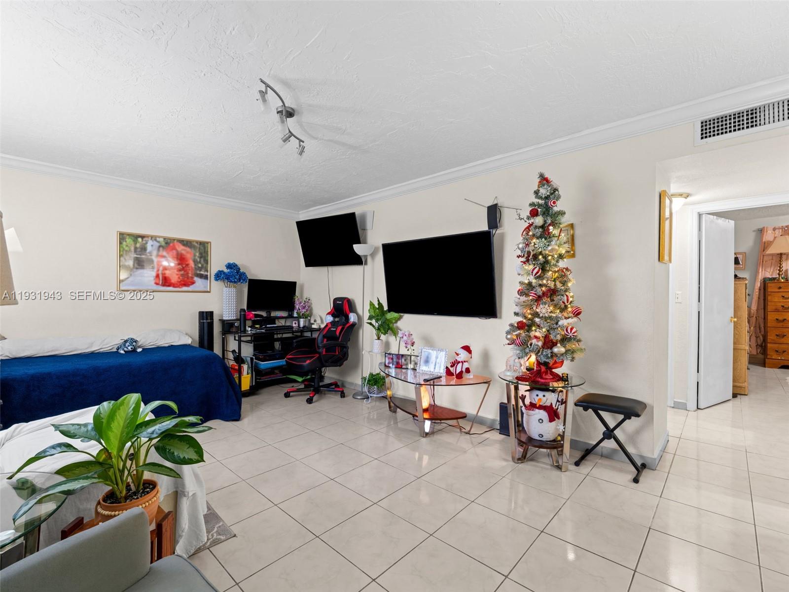 A living area features tiled floors, a wall-mounted television, a gaming chair, and a Christmas tree — 1655 W 44th Pl # 448, Hialeah FL 33012, HIALEAH, FL