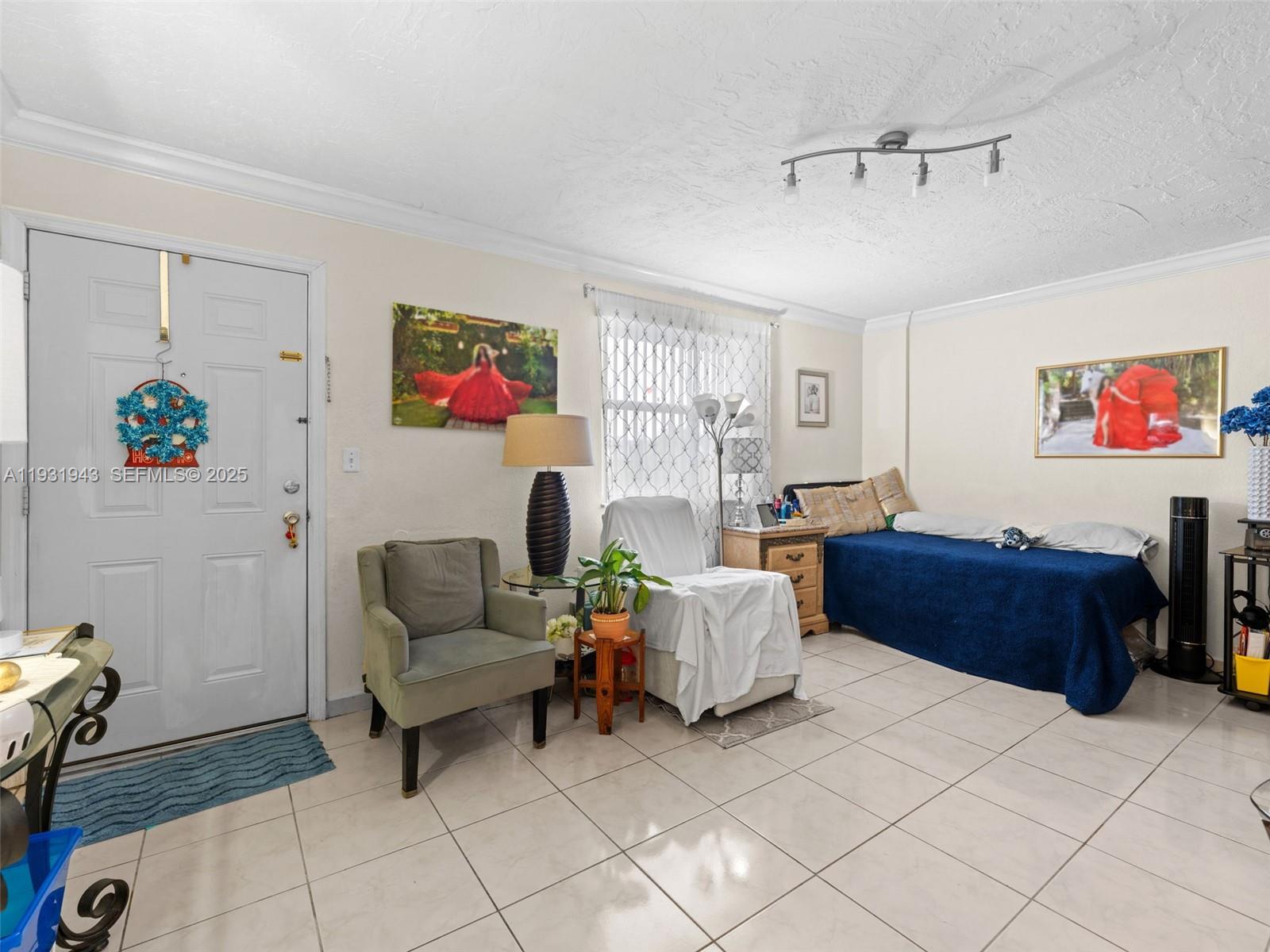 A room with tiled floors, a bed, a chair, and a white front door — 1655 W 44th Pl # 448, Hialeah FL 33012, HIALEAH, FL
