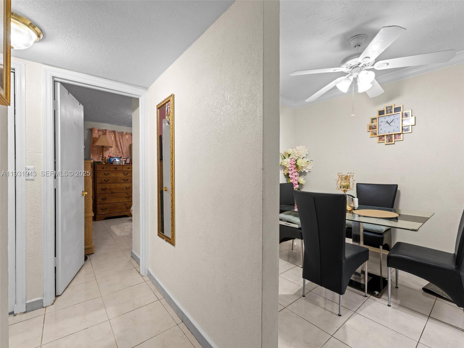 A dining area with a glass table and black chairs sits beside a tiled hallway — 1655 W 44th Pl # 448, Hialeah FL 33012, HIALEAH, FL