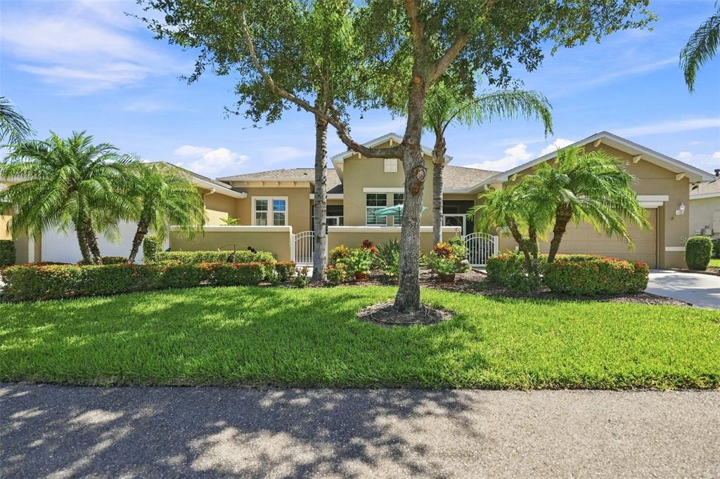 A single-story house with a tan exterior, palm trees, and a manicured lawn — 2109 SIFIELD GREENS WAY UNIT 70, SUN CITY CENTER, FL