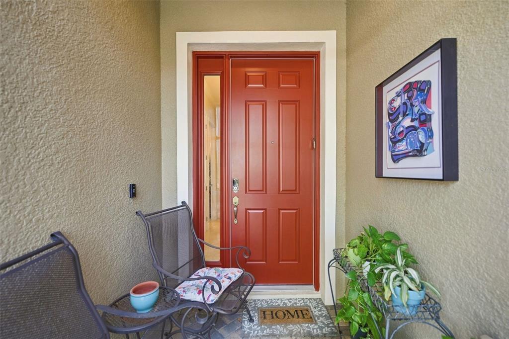 A front entryway features a red door, two metal chairs, and a small side table — 2109 SIFIELD GREENS WAY UNIT 70, SUN CITY CENTER, FL