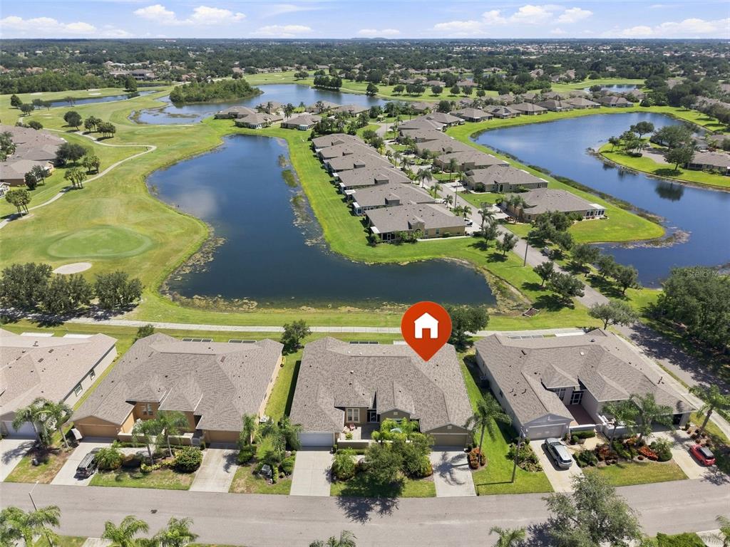 An aerial view shows a residential neighborhood with houses, a large pond, and golf course — 2109 SIFIELD GREENS WAY UNIT 70, SUN CITY CENTER, FL