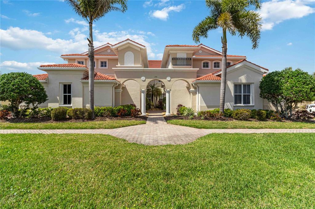 A two-story Mediterranean-style house with a tiled roof, arched entryway, and two palm trees — 133 BELLA VISTA TERRACE UNIT 32C, NORTH VENICE, FL