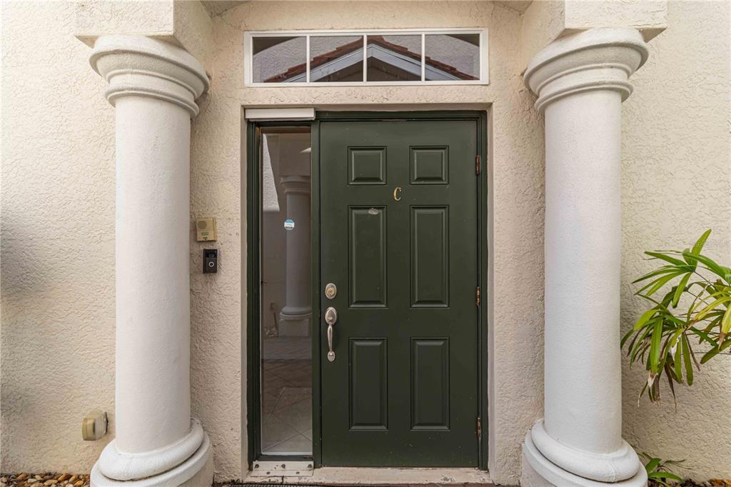 A dark green front door with a side window is flanked by two white columns — 133 BELLA VISTA TERRACE UNIT 32C, NORTH VENICE, FL