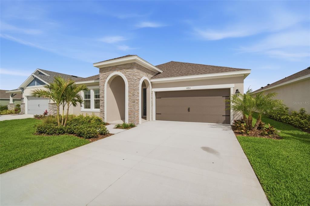 A single-story house with a stone-accented entryway, a two-car garage, and a concrete driveway — 11834 RICHMOND TRAIL, PARRISH, FL