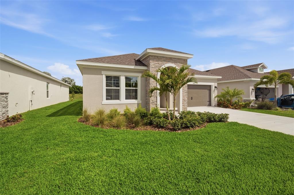 A single-story house with a beige stucco exterior, stone accents, and a front-facing garage — 11834 RICHMOND TRAIL, PARRISH, FL