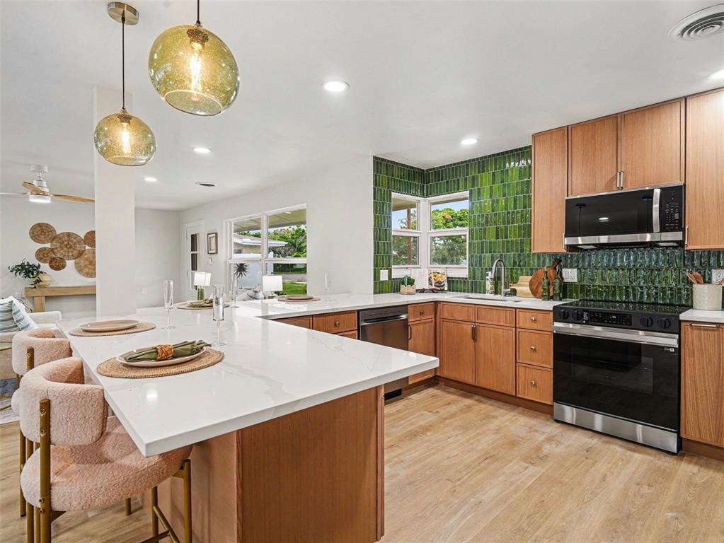A kitchen features wood cabinets, white countertops, and a green vertical tile backsplash — 9911 ROYAL PALM DRIVE, BRADENTON, FL