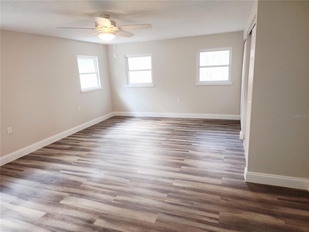 An empty bedroom features light-colored walls, a ceiling fan, and wood-look laminate flooring — 8150 SW 80TH TRAIL, TRENTON, FL