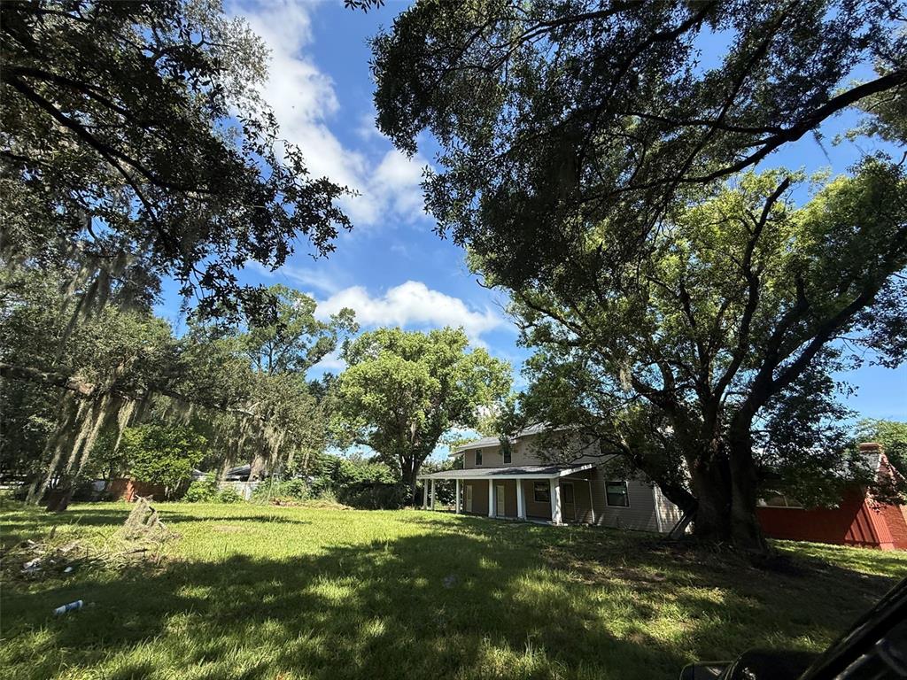 A two-story house with a front porch sits on a grassy lot under large trees — 2921 CRUTCHFIELD ROAD, LAKELAND, FL