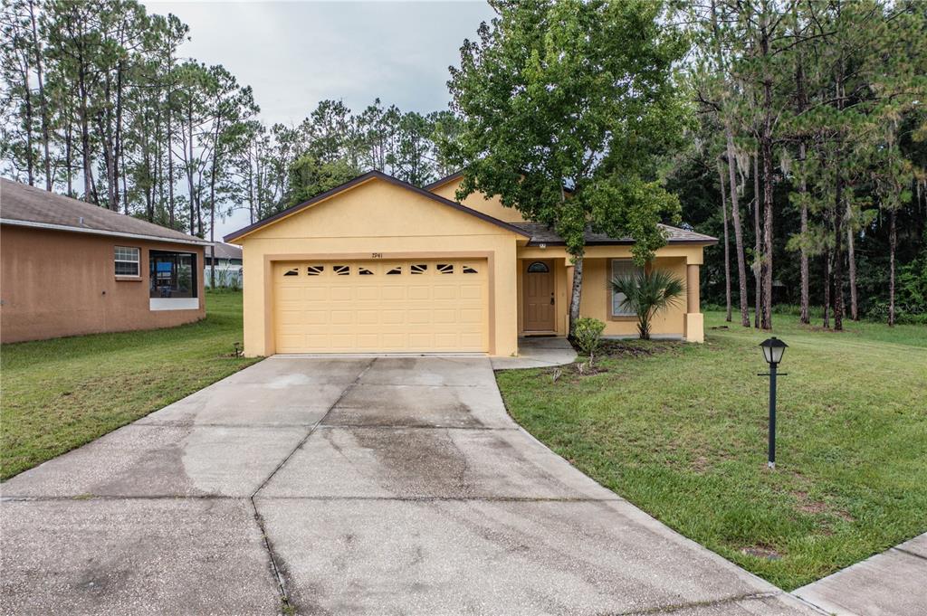 A yellow single-story house with a two-car garage and a concrete driveway — 7941 SUGAR PINE BOULEVARD, LAKELAND, FL