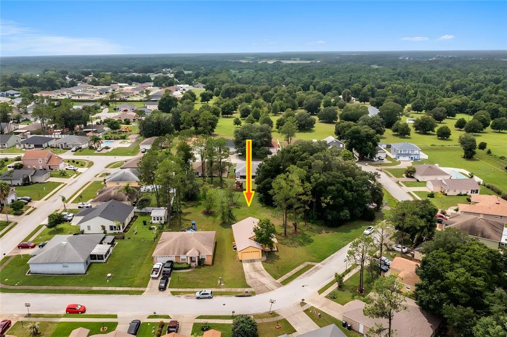 An aerial view shows a suburban house with a large, tree-filled backyard and yellow arrow — 7941 SUGAR PINE BOULEVARD, LAKELAND, FL