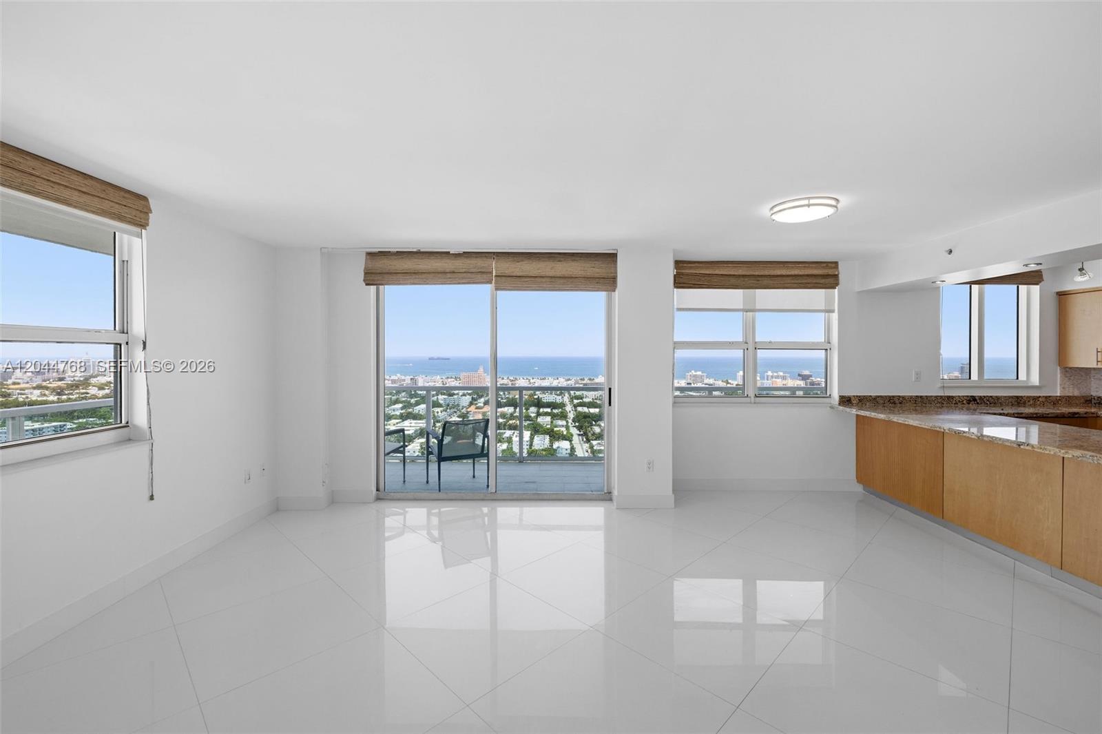 A bright living area features white tile floors, a kitchen counter, and balcony ocean views — 650 West Ave # 2912, Miami Beach FL 33139, MIAMI BEACH, FL