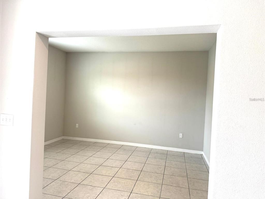 An empty room with light gray walls and light-colored square floor tiles — 863 HUDSON VALLEY DRIVE, POINCIANA, FL