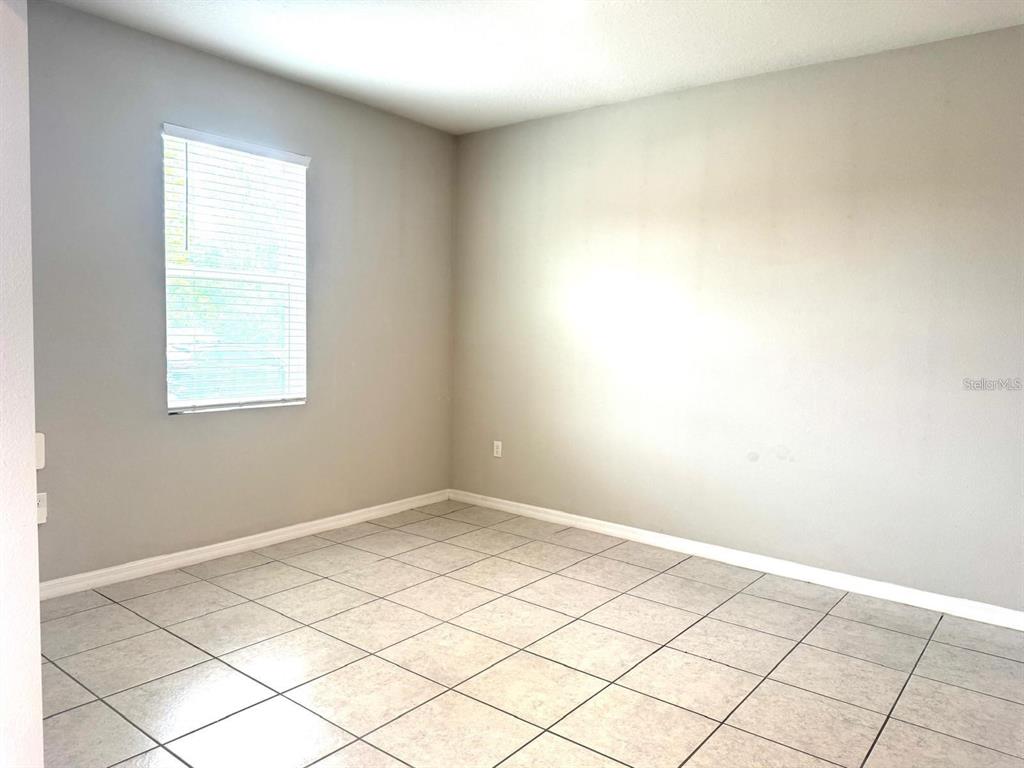 An empty room with light gray walls, a window with blinds, and tiled flooring — 863 HUDSON VALLEY DRIVE, POINCIANA, FL