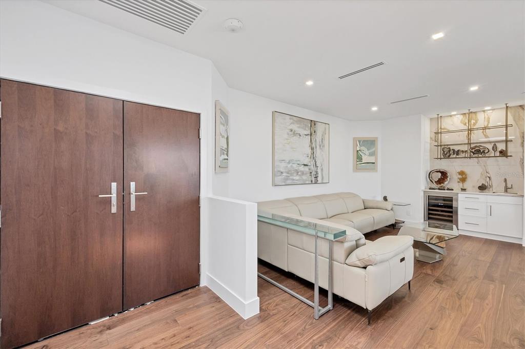A living room features a beige sectional sofa, wood flooring, and a built-in wet bar — 1211 GULF OF MEXICO DRIVE UNIT 1005, LONGBOAT KEY, FL
