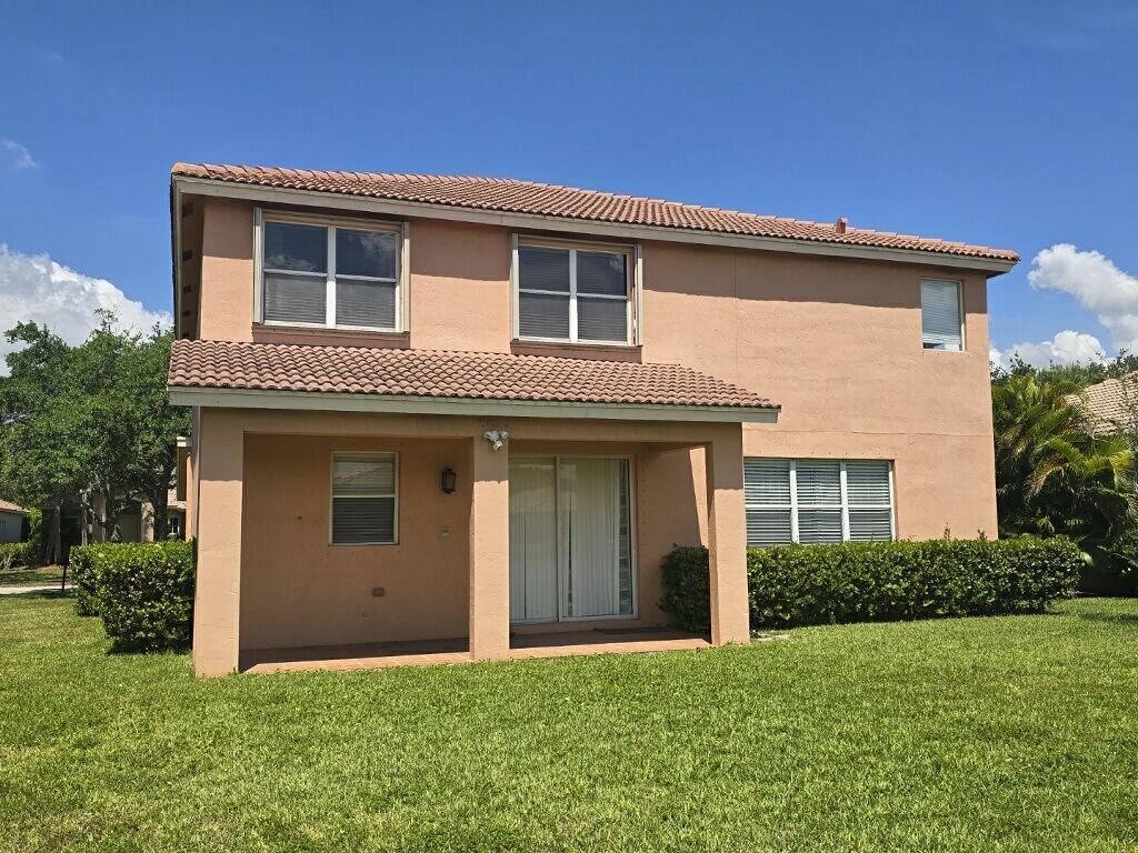 The rear exterior of a two-story peach-colored house features a covered patio and lawn — 4436 Laurel Place, Weston FL 33332, WESTON, FL