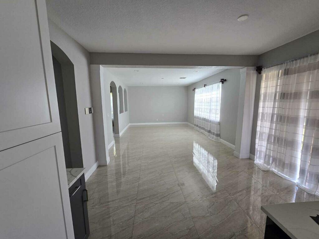 An empty room with light gray walls, large polished tile flooring, and white sheer curtains — 4436 Laurel Place, Weston FL 33332, WESTON, FL
