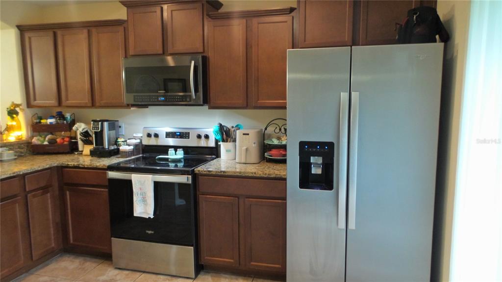A kitchen features dark wood cabinets, granite countertops, and stainless steel appliances — 2350 RICHWOOD PIKE DRIVE, RUSKIN, FL