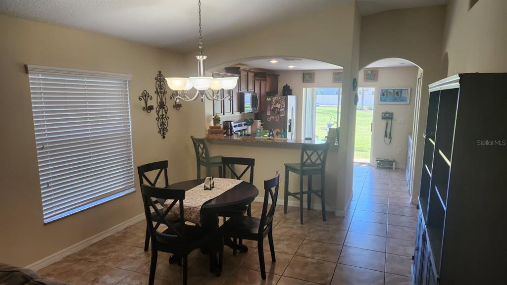 A dining area with a round table and breakfast bar opens into a kitchen — 2350 RICHWOOD PIKE DRIVE, RUSKIN, FL
