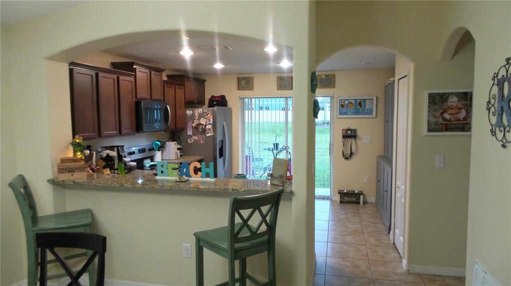 A kitchen with dark wood cabinets, granite countertops, and a breakfast bar with stools — 2350 RICHWOOD PIKE DRIVE, RUSKIN, FL