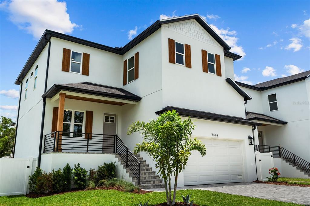 A two-story white house with brown shutters, a front porch, and a two-car garage — 7402 S SWOOPE STREET, TAMPA, FL
