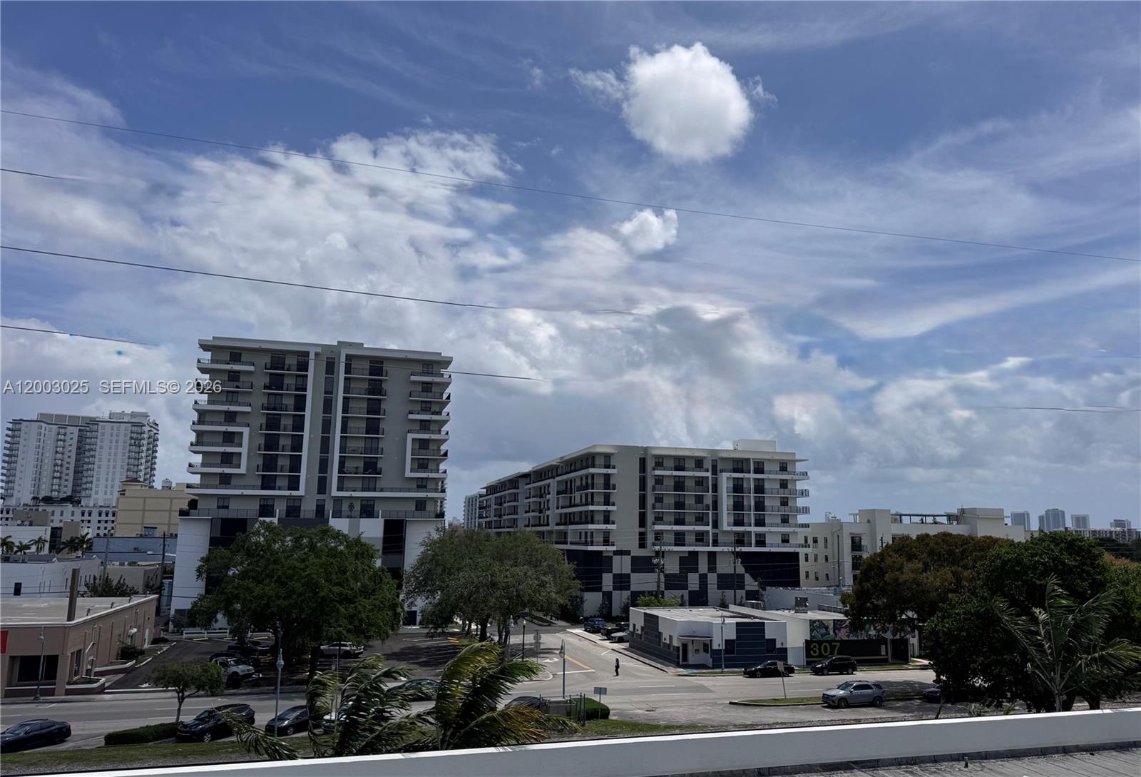 An exterior view shows two modern apartment buildings with balconies overlooking a street and parking — 2100 Van Buren St # 412, Hollywood FL 33020, HOLLYWOOD, FL