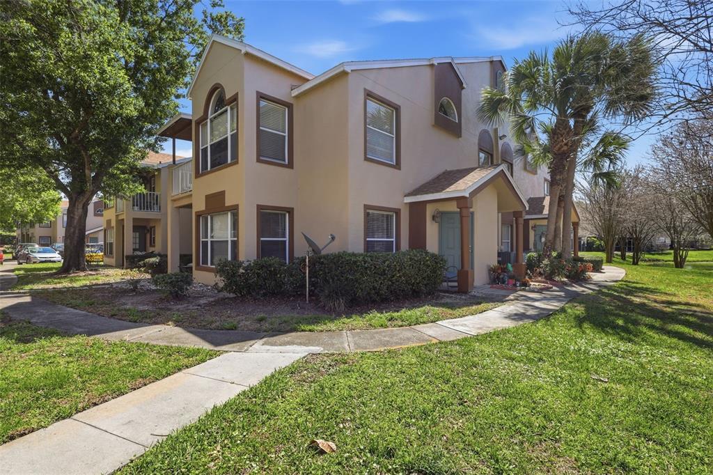 A two-story tan apartment building with brown trim, a sidewalk, and surrounding landscaping — 5452 E MICHIGAN STREET UNIT 5452-7, ORLANDO, FL