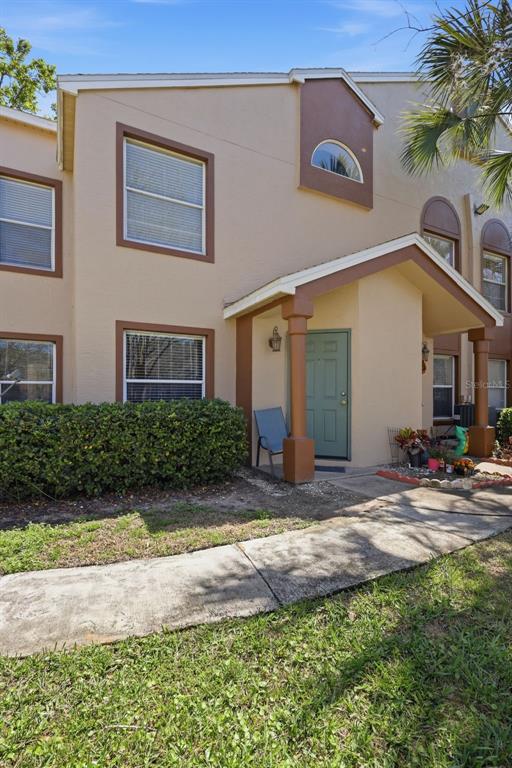 A two-story tan townhouse with a green front door and a concrete walkway — 5452 E MICHIGAN STREET UNIT 5452-7, ORLANDO, FL