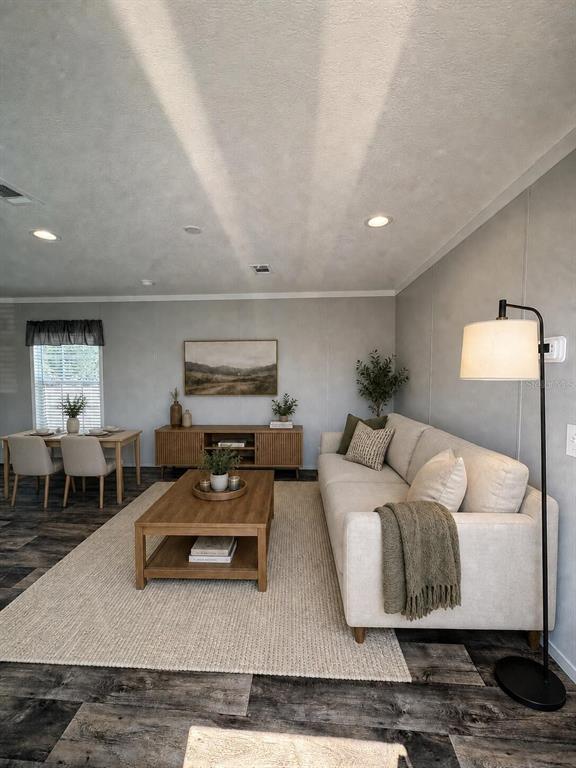 A living room features a beige sofa, wooden coffee table, and dining area with gray flooring — 6615 BANDURA AVENUE, NEW PORT RICHEY, FL