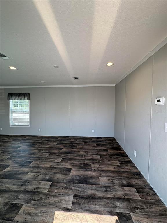 An interior view of a room with light gray walls, dark wood-look flooring, and recessed lighting — 6615 BANDURA AVENUE, NEW PORT RICHEY, FL